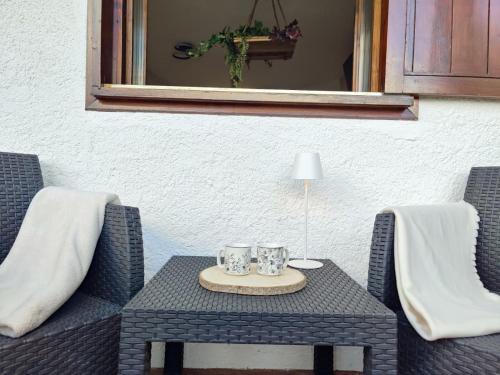 a table with two chairs and two mugs on it at Il Rifugio dell'Artista in Folgarida