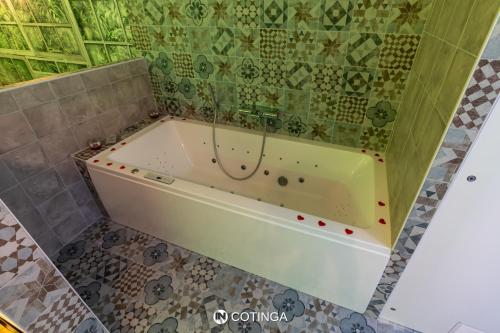a bath tub in a bathroom with a green tiled wall at Cotinga in Villars-les-Dombes