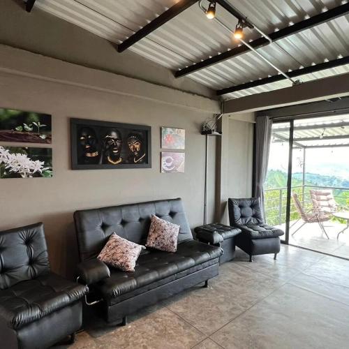 a living room with leather furniture and a balcony at Don Café - Luxury and confort in Manizales