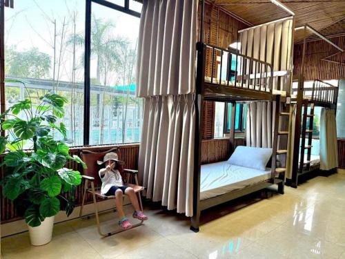une petite fille assise sur une chaise dans une chambre avec des lits superposés dans l'établissement May Garden Homestay Ninh Bình, à Phúc Trì