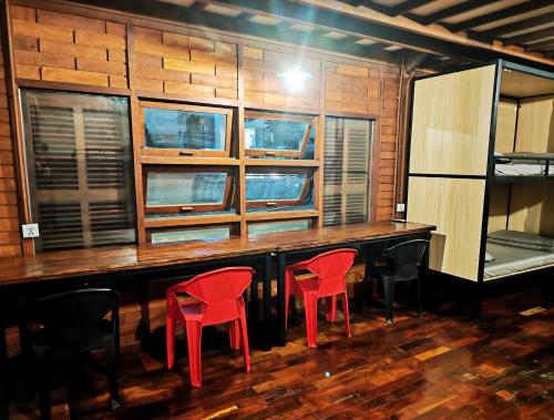 a bar with two red chairs and windows at Wood Wood Hostel in Vientiane
