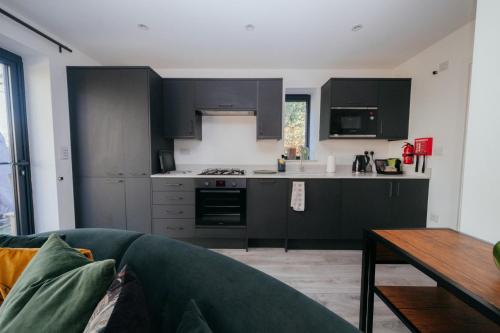 a kitchen with black cabinets and a blue couch at The Observatory Annexe in Dorking