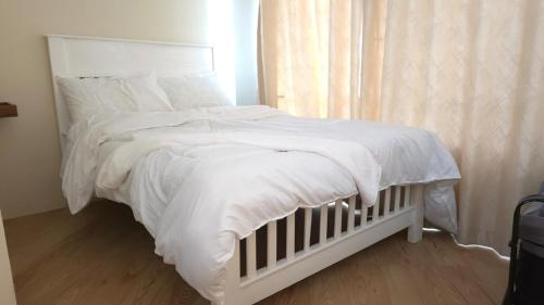 a white bed with white sheets and pillows at Serenity Gardens,pool retreat, Kigamboni in Dar es Salaam