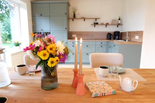 a table with a vase of flowers and candles on it at Ferienhaus Landliv Hus in Husby