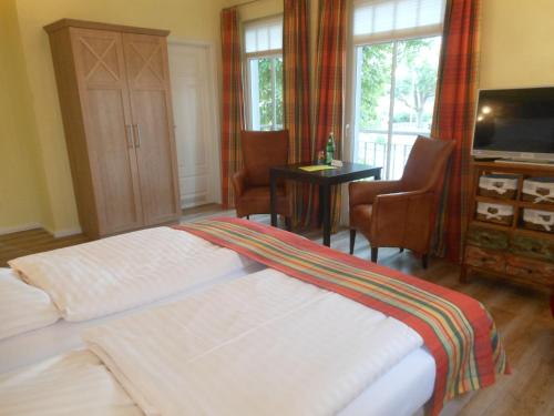 a bedroom with two beds and a television and a desk at Landhaus Hammoor Stieper Gastronomie GmbH in Hammoor