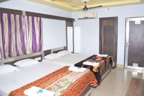 a hotel room with two beds and a window at Hotel Srikrishna International in Tarapith