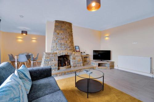 a living room with a couch and a stone fireplace at Oceanview Retreat & Private Parking in Saltdean