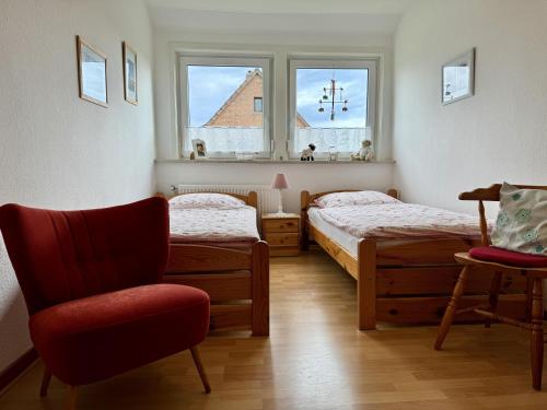 a bedroom with two beds and a chair and a window at Ferienwohnung Garmatter Hermannsburg in Hermannsburg