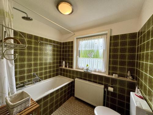 a green tiled bathroom with a tub and a window at Ferienwohnung Garmatter Hermannsburg in Hermannsburg