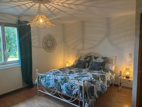 a bedroom with a bed and a chandelier at Les Chambres de Nath in Gevry