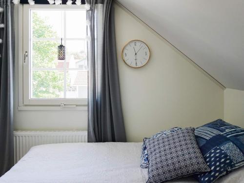a bed with a clock on a wall next to a window at 9 person holiday home in SOLLENTUNA-By Traum in Sollentuna