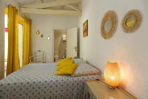 a bedroom with a bed with yellow pillows and a lamp at Le clos de la tour cassis piscine chauffée in Cassis