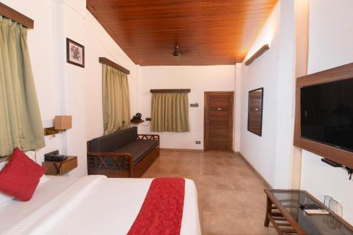 a bedroom with a bed and a couch and a tv at Vaarsa by Bay Hotels in Alibaug