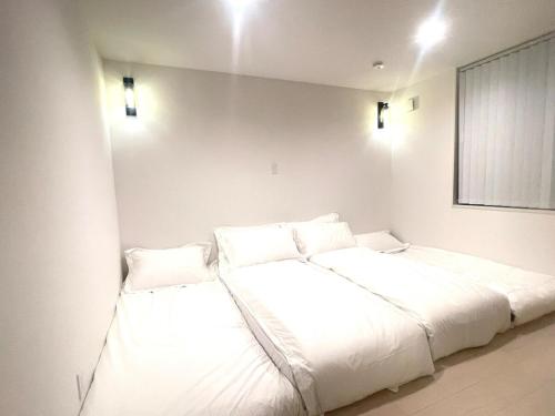two beds in a room with white sheets and pillows at Sunshine pool villa 2新築ラグジュアリーリゾートヴィラ天然芝ゴルフサウナ完備 in Katakai