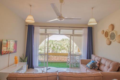 a living room with a couch and a large window at 2-BR House Diani Beach - 3 Min to Beach in Galu