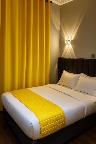 a bedroom with a large bed with yellow curtains at Hôtel Foham Oasis in Bandjoun
