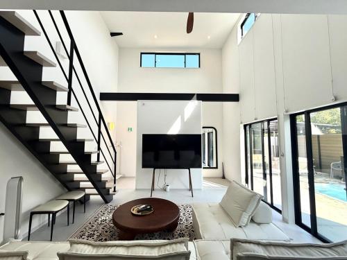 a living room with a large tv and a staircase at Sunshine pool villa 2新築ラグジュアリーリゾートヴィラ天然芝ゴルフサウナ完備 in Katakai
