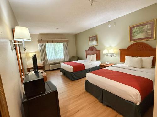 a hotel room with two beds and a flat screen tv at Americas Best Value Inn Wiggins in Wiggins