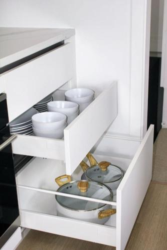 a white cabinet with white bowls and plates at 49 Cliff Retreat in Whangaparaoa