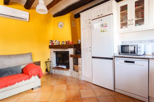 a kitchen with a white refrigerator and a fireplace at CASA RURAL LES ROQUETES in Ráfales