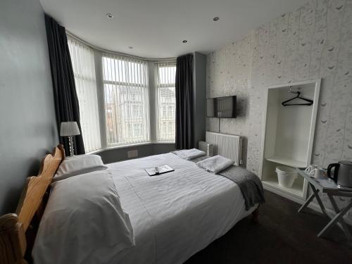 a bedroom with a large white bed and windows at The Villa Hotel in Blackpool