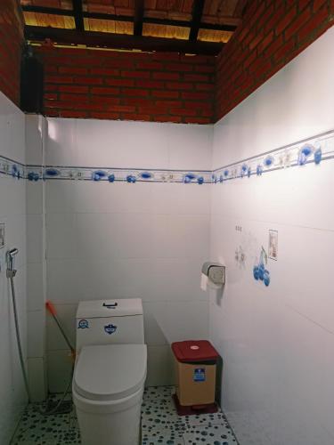 a bathroom with a white toilet and a red brick wall at Hương Rừng Nam Cát Tiên in Tân Phú