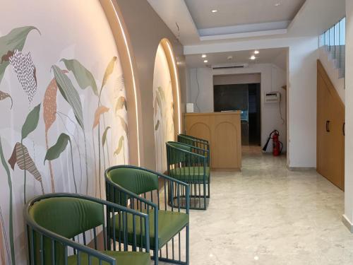 a row of green chairs in a hallway with a mural at Hotel Sagar Presidency A Unit of Buesoco Hospitality Private Limited in Daman