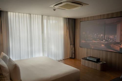 a bedroom with a white bed and a large window at Richmann Resort Hotel Hatyai in Hat Yai