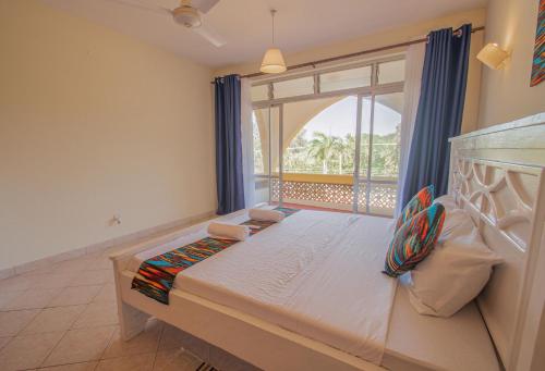 a bedroom with a bed and a large window at 2-BR House Diani Beach - 3 Min to Beach in Galu