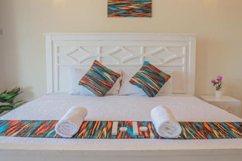 a white bed with two towels and pillows on it at 2-BR House Diani Beach - 3 Min to Beach in Galu