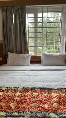 a bed in a bedroom with a large window at Sonam hotel and restaurant in Kushālnagar