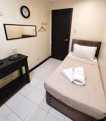 a room with two beds and a clock on the wall at Amax Inn Makati in Manila