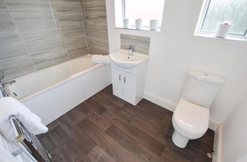 a bathroom with a toilet and a sink and a tub at Coastal Corporate Stays in Blythe