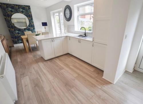 a kitchen with white cabinets and a wooden floor at Coastal Corporate Stays in Blythe