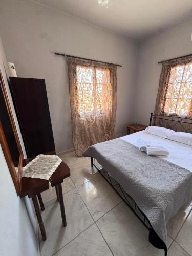 a bedroom with a bed and a chair and two windows at PANKO Suite in Dhímitra