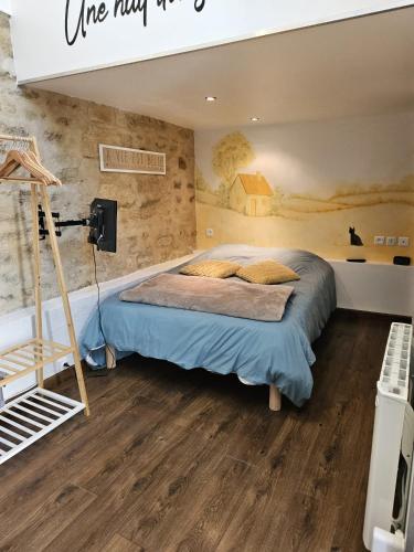 Un dormitorio con una cama y suelo de madera. en Une nuit dans le Vexin, en Cléry-en-Vexin