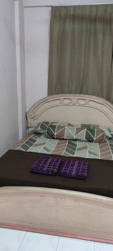 ein Bett mit einem hölzernen Kopfteil und Kissen darauf in der Unterkunft Mia Homestay in Kuala Terengganu