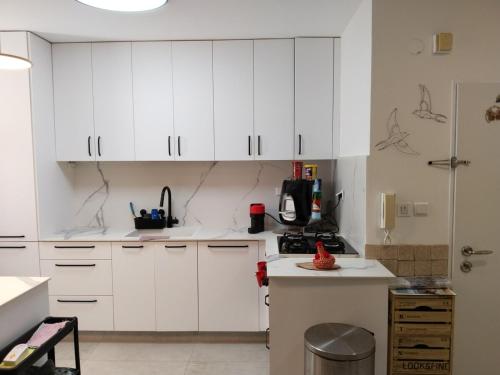 a white kitchen with white cabinets and a counter at Rony's Place in Ramat Gan