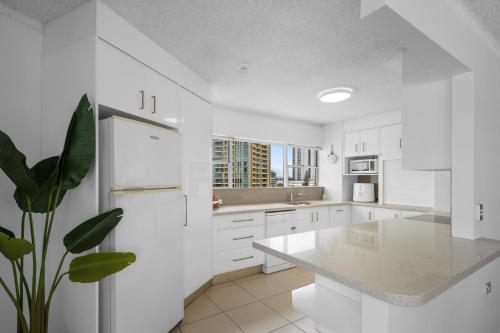 een keuken met witte kasten en een witte koelkast bij Pacific Plaza Apartments in Gold Coast