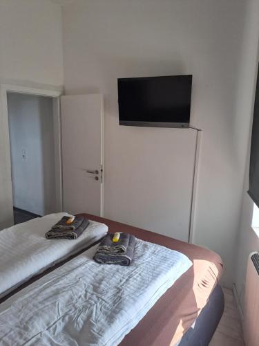 two beds in a room with a tv on the wall at Zimmer am Hauptbahnhof 1 in Minden