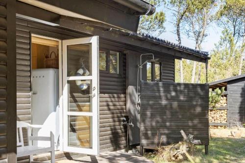a small house with an open door and a refrigerator at TV1517-Albaek-Jasonvej-1 in Horsnab