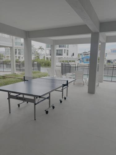 due tavoli da ping pong in una grande stanza con sedie di Brand New Luxury Build 265 Carolina Ave- Heated Pool, Hot Tub home a Fort Myers Beach