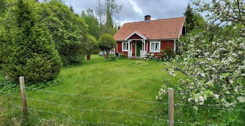 a red house with a fence in front of a yard at KRO414-Loenashult-Norra-Ebboen-1 in Tvetaryd