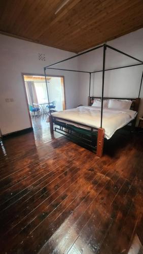 una camera con letto a baldacchino e pavimento in legno di Tiga Ciene Guest House a Kikuyu