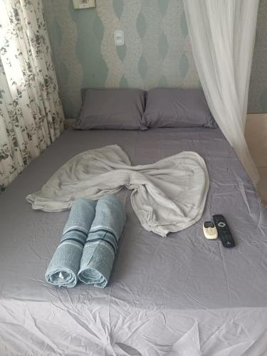 a bed with a blanket and some towels on it at loft barbudo in Araruama