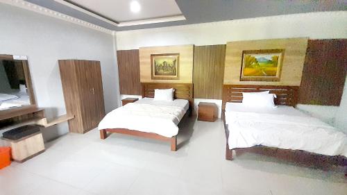 a bedroom with two beds and a television in it at Montana Hotel Kuningan in Panawuan