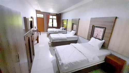 a room with three beds and a mirror at Montana Hotel Kuningan in Panawuan
