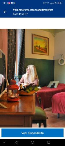 a woman sitting at a table in a hotel room at Villa Amaranta Room and Breakfast in Edolo