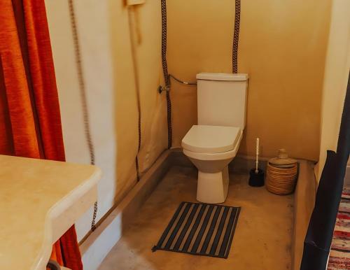 a small bathroom with a toilet and a rug at Luxurious Merzouga Desert Camps in Merzouga