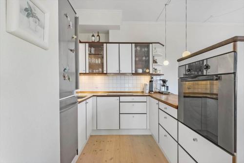 a kitchen with white cabinets and a wooden floor at 1469-N-Hornbaek-Kystvej-34-lej-2 in Hornbæk